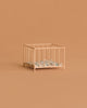 A small, empty Maileg Playpen, My - Rose sits against a beige background, featuring a patterned blanket inside.