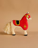 The Holztiger Tournament Horse, Red ships in one week and features a handmade cream wood body, red saddle with yellow cross, black hooves, and cream yarn tail. Made from maple and beech wood. Shown against a beige background.