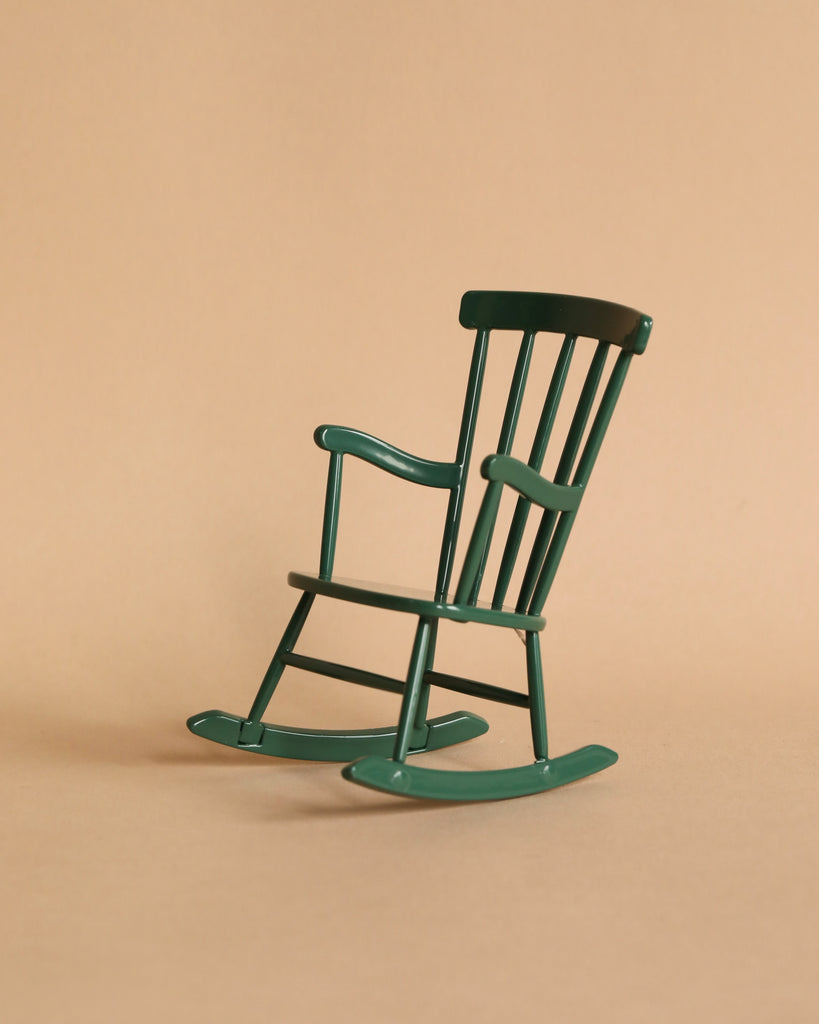 The Maileg Cozy Green Room Set features a small green wooden rocking chair with classic slats and curved rockers, perfect for Maileg mouse furniture. The chair is displayed on a plain beige background, angled slightly to the left.