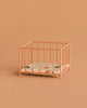 A small Maileg Playpen, Micro - Dark powder stands on a matching background. Inside, a thin mattress with a green and brown floral pattern adds charm to this micro-sized playpen.