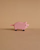 A pink Holztiger Handmade Wooden Farm Animals Set pig with a rope tail and black-painted feet.