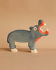 The Holztiger Hippo, a handcrafted wooden figurine painted blue with an open mouth showing white teeth and pink insides, stands on a beige surface against a matching background. Ships in one week.