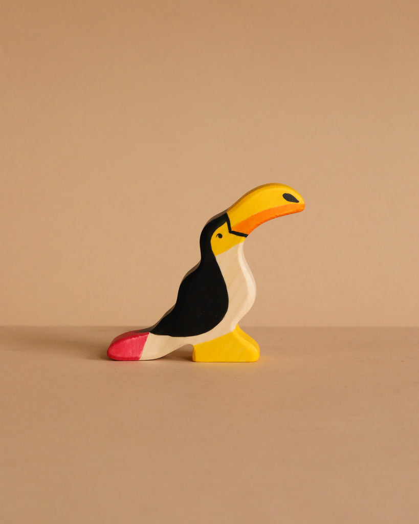 Holztiger Handmade Wooden Birds of the World Set toucan figurine with a yellow beak, black body, and red tail tip.