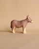 Against a tan background, the Handmade Wooden Donkey stands proudly. This charming clay figurine has a brown body with cream legs, muzzle, and inner ears. Its simple design showcases small eyes and no mouth—a testament to handcrafted linden wood artistry.