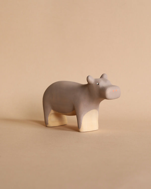 The Handmade Wooden Hippo is a small, minimalist sculpture with a smooth, pale brown surface and soft, rounded features. It is crafted with child-safe paint against a plain beige background.