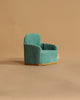 A small, teal armchair with gold trim from the Maileg Family Room Set sits on a plain beige background, perfect as charming dollhouse accessories or Maileg mouse furniture.
