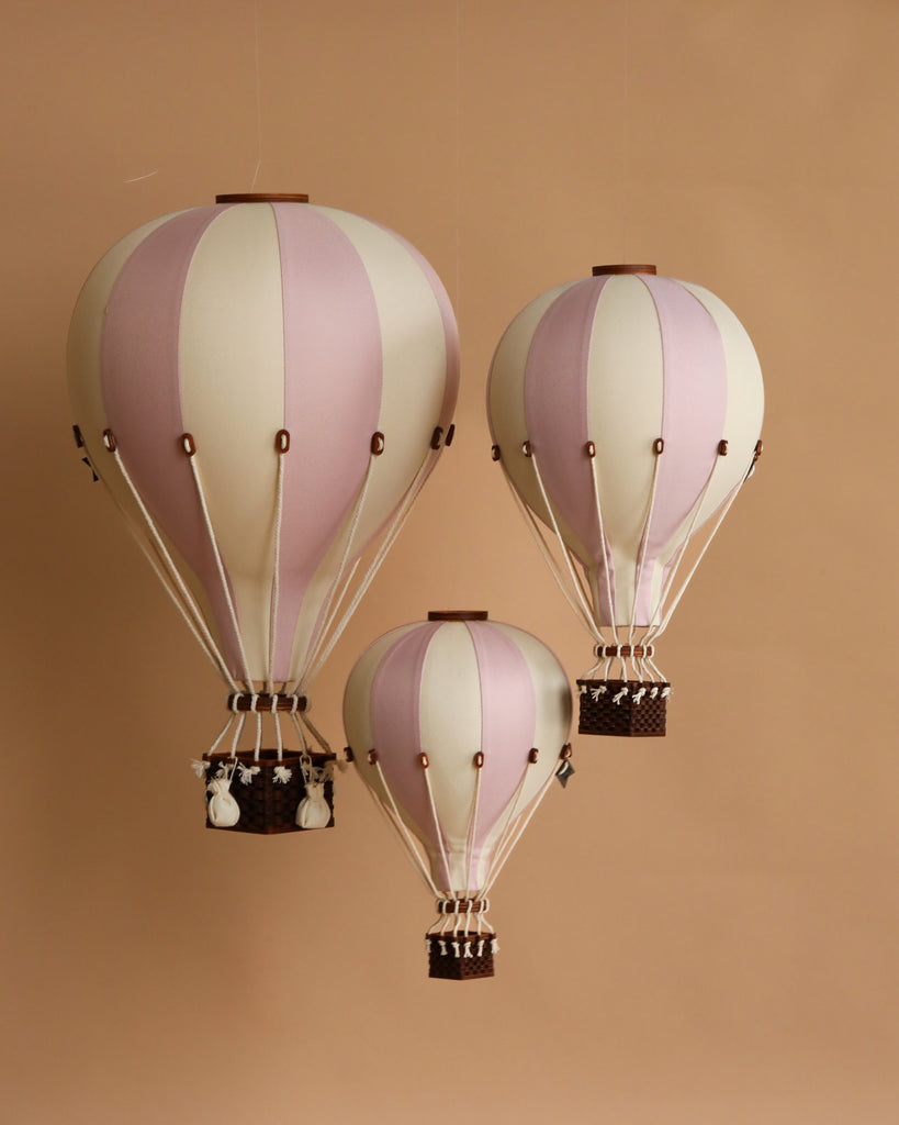 Three pastel lilac and white striped Hot Air Balloon - Lilac decoration models hang against a plain beige background, each with a small basket—perfect handmade decor for children's rooms.