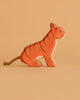 The Ostheimer Handmade Wooden Tiger Set features a small, handcrafted wooden tiger with painted stripes and a rope tail, displayed on a plain, light brown background.