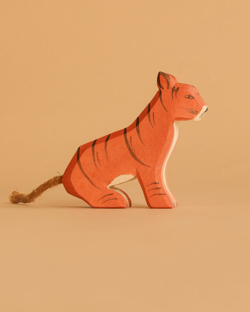 The Ostheimer Handmade Wooden Tiger Set features a small, handcrafted wooden tiger with painted stripes and a rope tail, displayed on a plain, light brown background.
