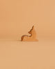 A small, handcrafted deer figurine with white spots from the Ostheimer Handmade Wooden Woodland Set sits against a light brown background, showcasing the timeless charm of these classic toys.