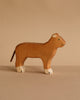 Part of the Holztiger Handmade Wooden Safari Animals Set, this wooden lioness is crafted from maple and beech wood, with painted details including green eyes, white-tipped paws, and a simple tail, shown on a neutral beige surface.
