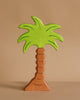 The Holztiger Palm Tree is a handcrafted wooden figure featuring a brown trunk and bright green leaves, shown standing upright against a plain beige background.