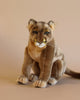 A realistic plush model of a Mountain Lion Stuffed Animal sitting against a plain background, featuring detailed fur, whiskers, and striking eyes, bringing out its unique personality.
