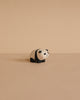 The Handmade Tiny Wooden Panda Child, crafted from Albizia wood, stands on a beige surface with a matching background, highlighting the charming artistry of Bali's skilled artisans.
