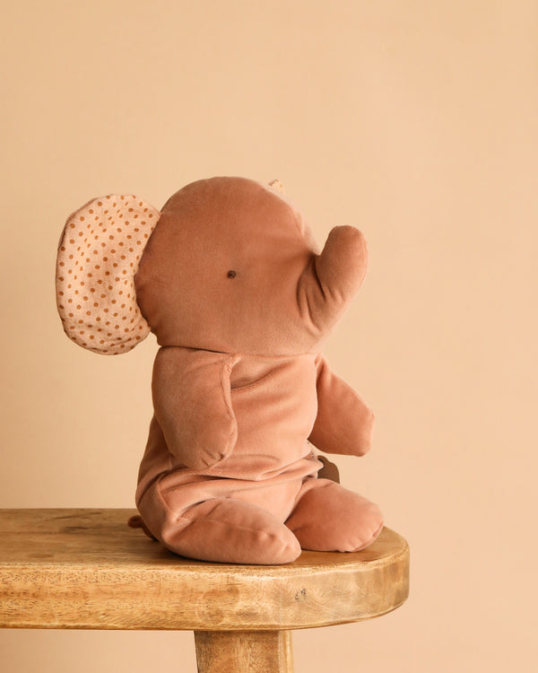 The Maileg Elephant Soft, Medium - Vintage Rose is a plush toy with vintage rose fabric and polka-dotted inner ears, shown sitting on a wooden stool against a beige backdrop—ideal for stuffed animal and Safari friends lovers.