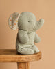 The Maileg Elephant Soft, Medium - Iron Grey, is a charming light gray stuffed toy made from recycled polyester plush. Sitting upright with polka-dotted inner ears, it adds a delightful touch to any space.