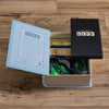 The Game of Life Vintage Bookshelf Edition board game sits open on a wooden floor, showing the box lid, instructions, play money, and green spinner—a classic collectible for fans.