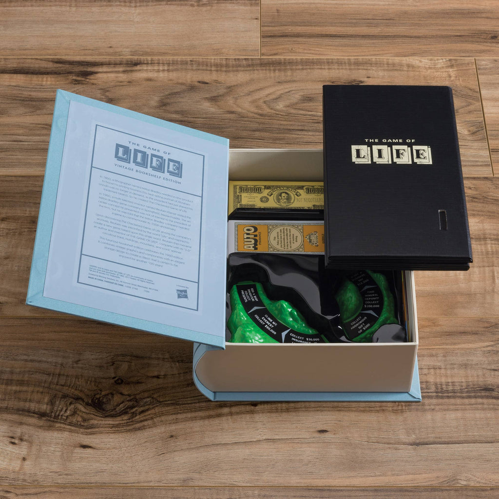 The Game of Life Vintage Bookshelf Edition board game sits open on a wooden floor, showing the box lid, instructions, play money, and green spinner—a classic collectible for fans.