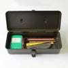 Open black Multi Purpose Steel Storage Box T-320 containing a notebook, several pencils, a yellow ruler, and a metal utility knife.