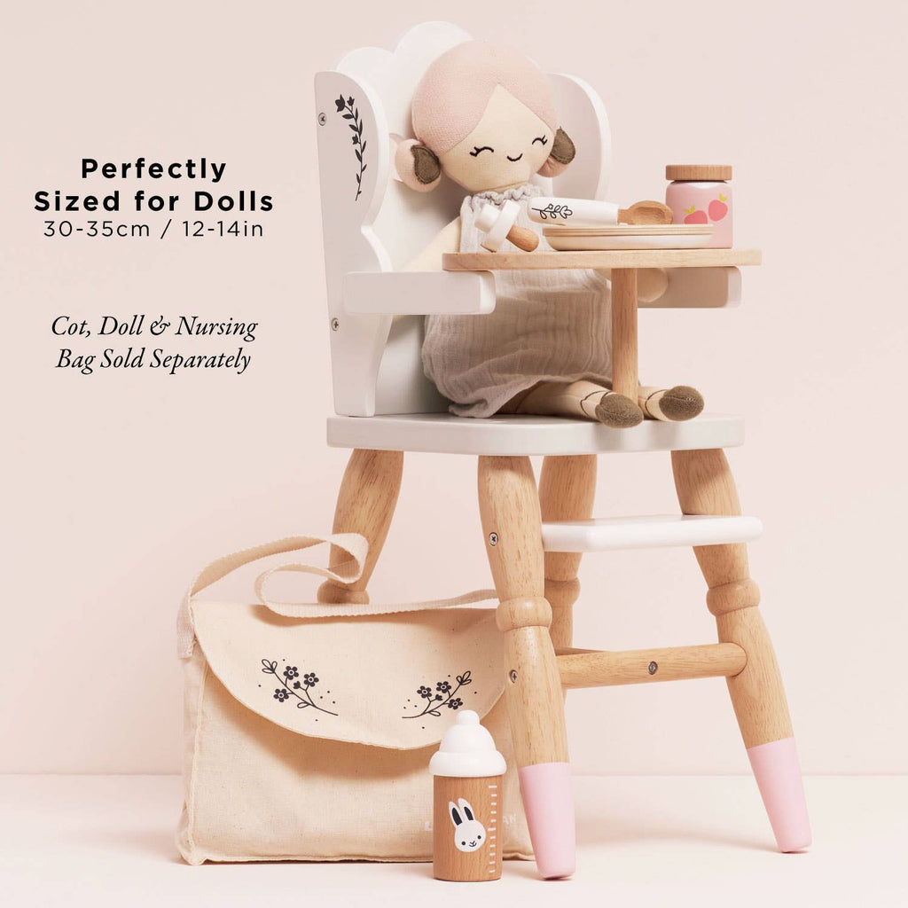 The Dolls Wooden High Chair features pink-tipped legs and fits dolls 30-35cm (12-14in). Includes a small bottle, cup, and cream-colored cloth bag. Eco-friendly. Cot, Doll & Nursing Bag sold separately.