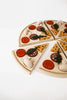 A Sabo Concept Wooden Pizza sliced into eight pieces, each topped with various colorful play toppings such as mushrooms, tomatoes, and leaves, arranged on a white background.