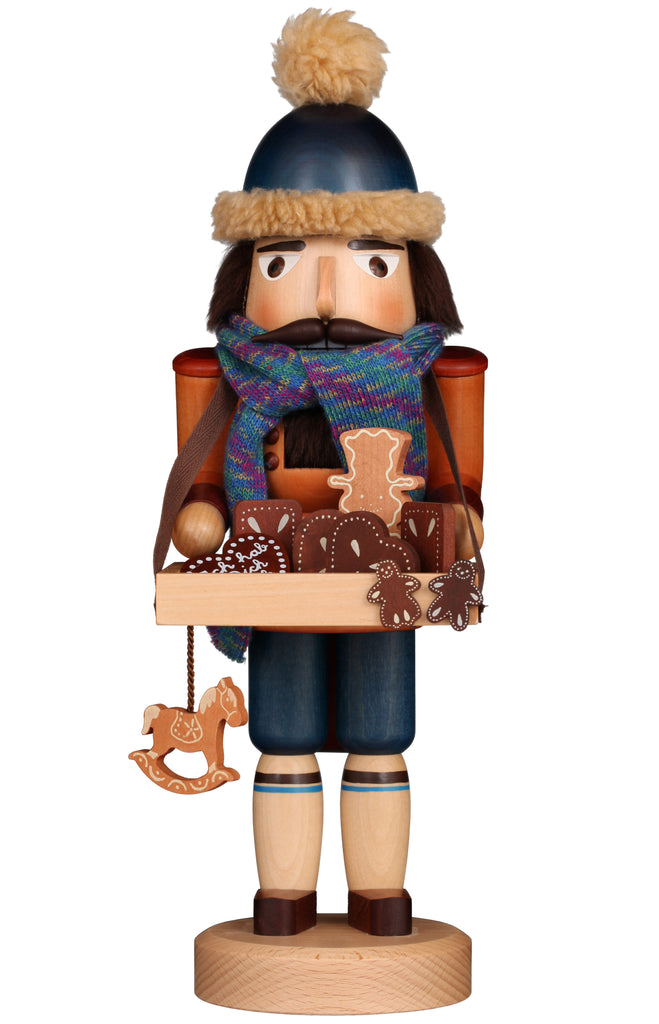 The "Christian Ulbricht Collectible Wooden Nutcracker - Gingerbread Vendor" showcases a unique combination of traditional craftsmanship and German artistry. This limited-edition piece features a vibrant blue hat with furry trim, a colorful scarf, and holds a tray adorned with gingerbread cookies and a miniature rocking horse. Its detailed painted design captures the timeless charm of classic nutcrackers.