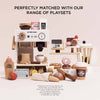 A collection of wooden cafe playsets—including a coffee machine, smoothie blender, snacks, and our Artisan Bread and Knife Set (ships in one week)—perfect for role play. Text above reads: “Perfectly matched with our range of playsets.”.
