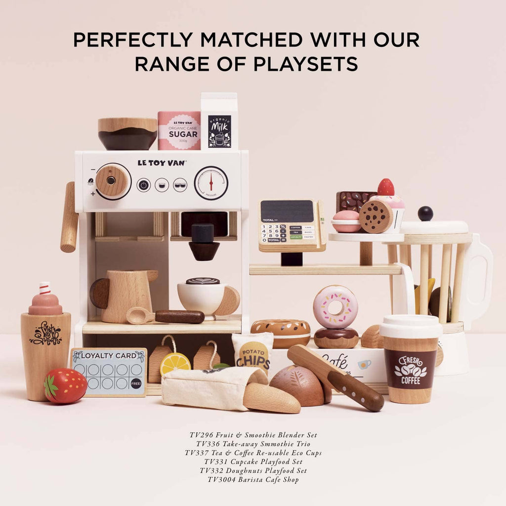 A collection of wooden cafe playsets—including a coffee machine, smoothie blender, snacks, and our Artisan Bread and Knife Set (ships in one week)—perfect for role play. Text above reads: “Perfectly matched with our range of playsets.”.