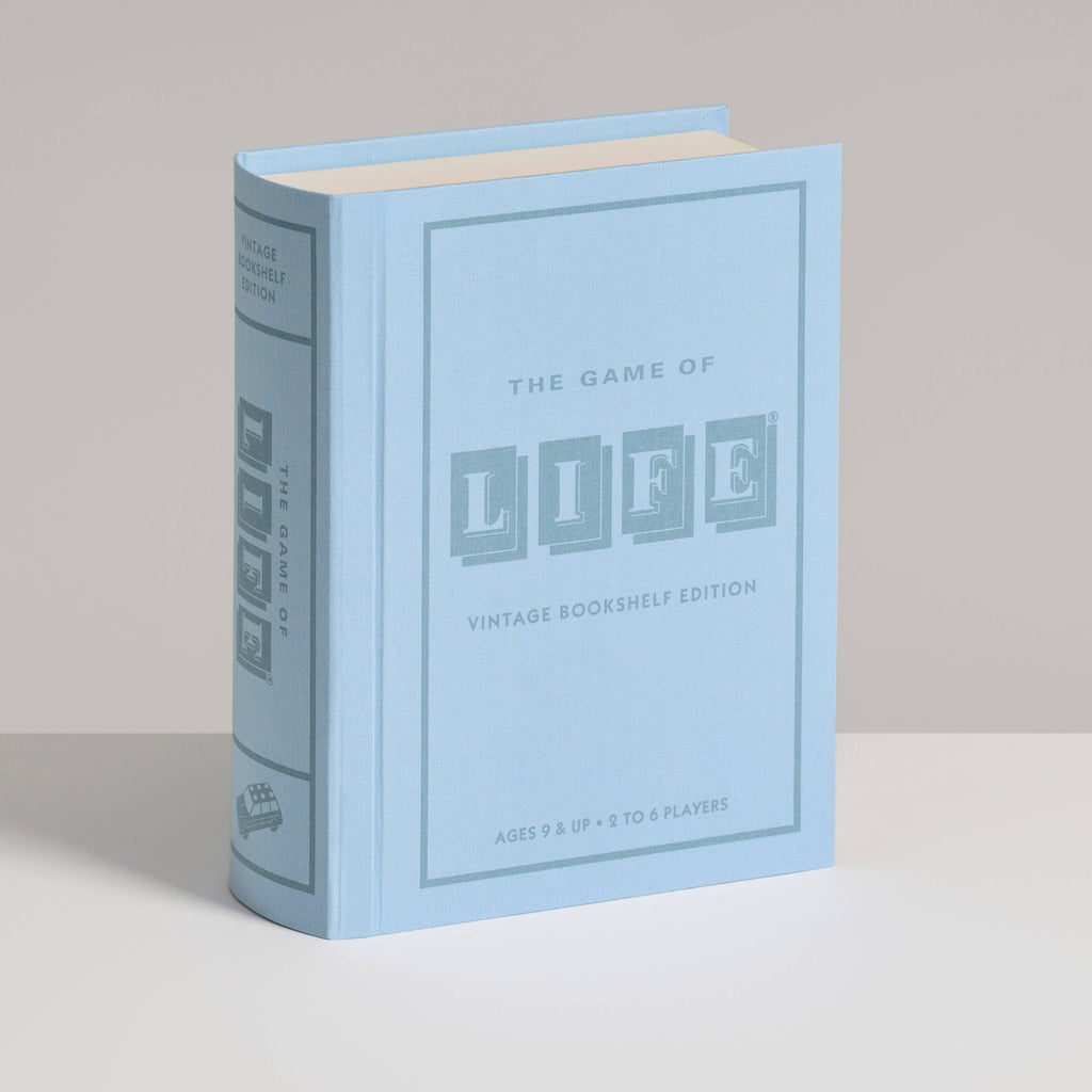 The Game of Life Vintage Bookshelf Edition, a light blue book-shaped box with minimalist gray and white accents, is designed to resemble a hardcover book—perfect for stylish display on your shelf.