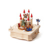 This Christmas Castle Music Box features a miniature castle with red-roofed towers, a decorated Christmas tree, and a reindeer pulling a blue sleigh.