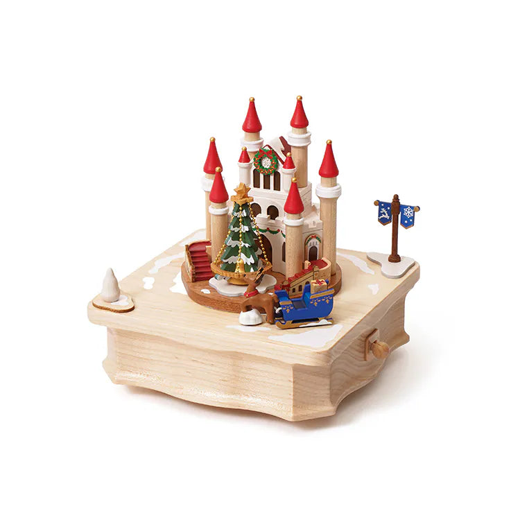 This Christmas Castle Music Box features a miniature castle with red-roofed towers, a decorated Christmas tree, and a reindeer pulling a blue sleigh.