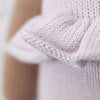 Close-up of Cuddle + Kind Violet the Fawn’s soft, light purple premium cotton knit with ruffled edge, highlighting detailed stitches. A brown texture appears in the background.