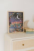 The Mischief Under the Moonlight 300 Piece Puzzle, featuring a whimsical forest scene with animals under a crescent moon, sits on a light dresser beside stacked children’s books and a plush crescent moon toy.