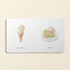 Part of "Our Little Library Vol. 2," a minimalist illustration enhances baby vocabulary with a vanilla ice cream cone on the left and a layered cake slice with white frosting and sprinkles on the right, each image labeled like pages from a first words board book.