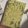 The Peter Pan | Barrie | Collector's Edition | Hardcover Book features an illustrated cover with fairies, plants, and whimsical green and gold designs evoking Never-Never Land’s magic under soft sunlight.