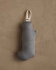The Coral & Tusk Puppy Stocking Ornament, a small gray Michigan-shaped fabric Christmas stocking with a cream loop for hanging, is displayed against a textured brown wall.