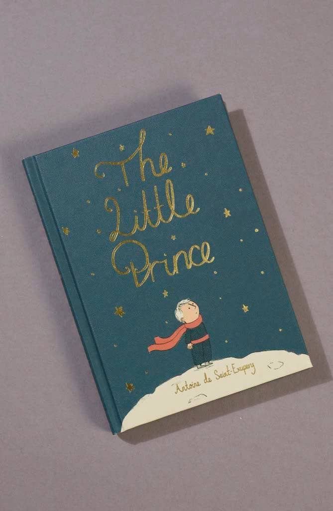 The Little Prince | Collector's Edition | Hardcover features a blue cover with gold stars and lettering, plus an illustration of the Little Prince in a red scarf standing on a white hill.