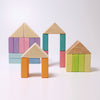 Four small structures crafted from the Pastel Duo Block Set are arranged on a white surface against a white background. Each structure showcases geometric shapes with rectangular blocks forming the walls and triangular blocks creating the roofs, highlighting the charming simplicity of their design.