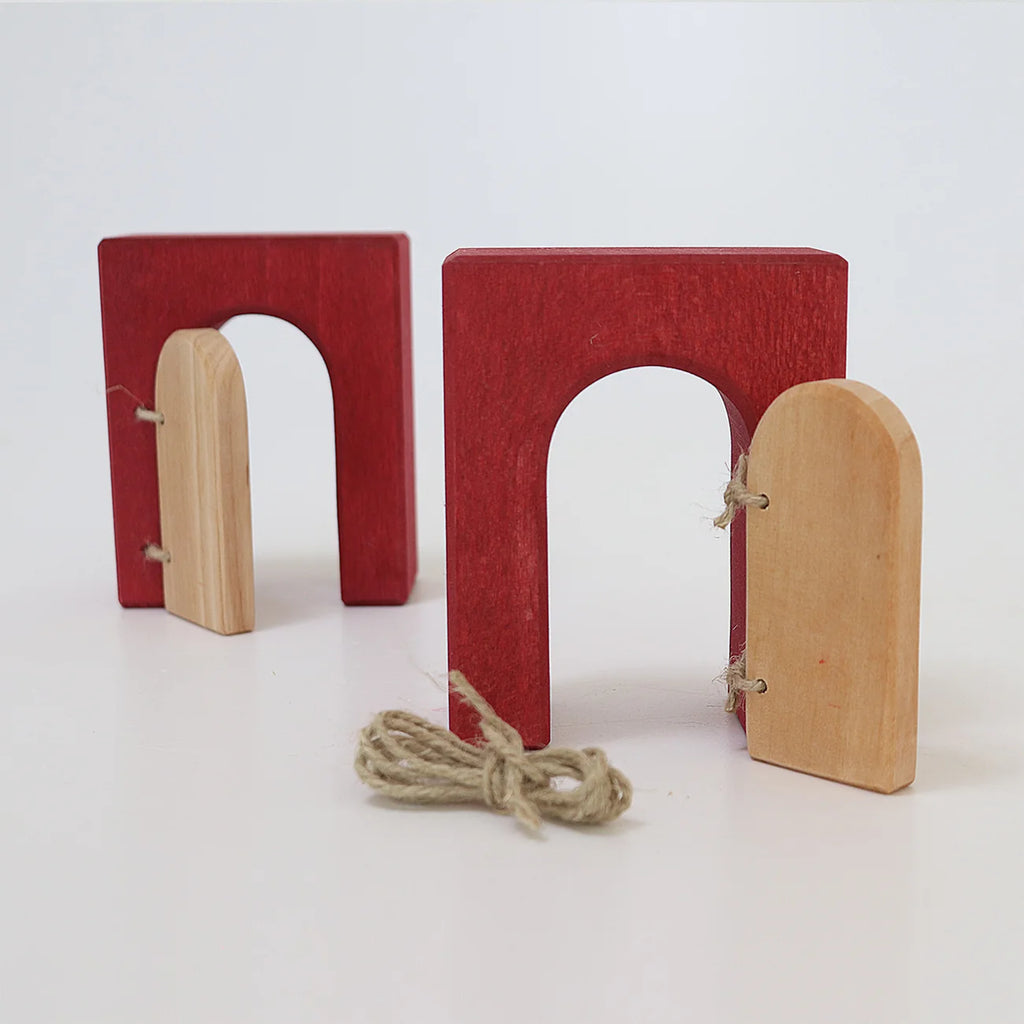 Two red wooden archways with attached light-wood doors and a loose piece of twine from the Grimm’s Building World - Desert Sand set, displayed on a white surface for imaginative free building.