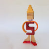 A human-like figure made of stacked wooden blocks from the Grimm’s Building World - Desert Sand set, featuring shades of yellow, orange, red, and purple, perfect for imaginative free building.