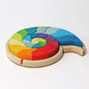 Grimm’s Building Set Ammonite Shell featuring colorful, curved wooden building blocks arranged in a spiral ammonite shell shape within a circular tray.