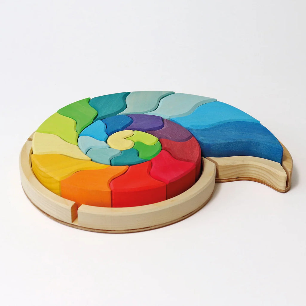 Grimm’s Building Set Ammonite Shell featuring colorful, curved wooden building blocks arranged in a spiral ammonite shell shape within a circular tray.