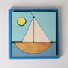 Grimm's Building Set - Blue: Colorful wooden blocks arranged in a blue square frame form a sailboat scene with water and a yellow sun—perfect toddler toys for creative play.