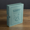 A teal box labeled "Sorry! Vintage Bookshelf Edition" sits on wood. This collectible edition, for ages 6+, suits 2–4 players and features two game pieces outlined on the cover.