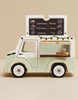 The Mobile Café Van is a vintage wooden toy with a chalkboard menu listing cappuccino, mocha, iced latte, cocoa, espresso, and tea. It has a serving window with cups and string lights—perfect for imaginative play.