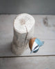 The Hand Carved Ornament - Red Breasted Nuthatch Bird (8"H) features a colorful, handmade wooden figurine perched sideways on a light, vertical sustainable softwood log, displayed on a pale wooden surface with a simple background.