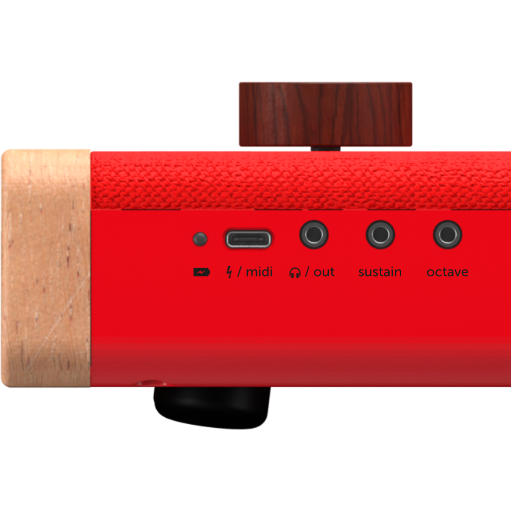 Close-up of the Loog Piano’s side panel, showing USB/MIDI, headphone out, sustain, and octave ports. The wood and fabric finish is accented by a large brown knob on top.
