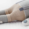 The Cuddle + Kind Noah the Dog, a fair trade hand-knit doll, rests on a white surface, displaying thoughtful craftsmanship and ethical sourcing.