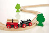 The BRIO Little Forest Train Set features a wooden toy train with a black engine, red log car, curved track, and two green tree figures—ideal for any BRIO collection or as a delightful train starter set.
