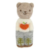 The Blabla Organic Alpaca Wool - Happy Go Lucky Bear Doll features a handmade beige head, small ears, and a smiling face, plus an orange apple sweater and gray pants with green trees—all crafted from soft organic alpaca fleece.